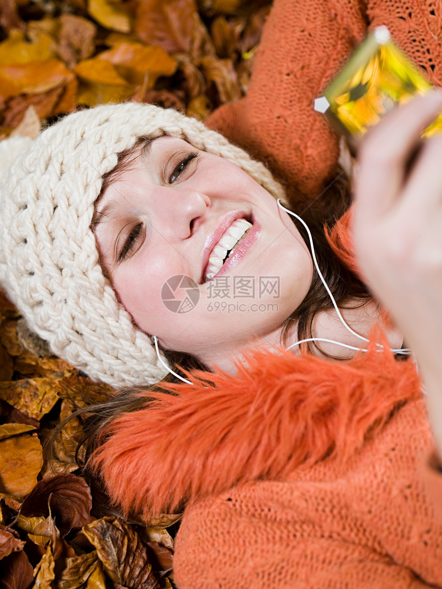 在秋叶上听音乐的女人图片