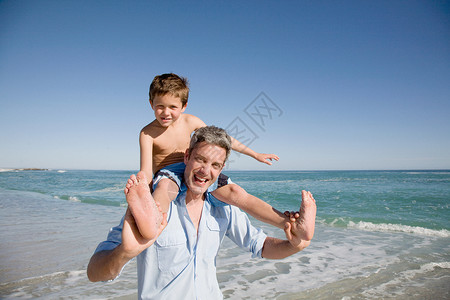 父亲肩扛在海边的男孩图片