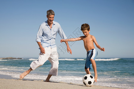 父子俩在海边踢足球背景图片
