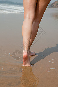 在湿沙上行走的女人的腿图片