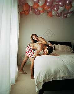 夫妇微笑着在床上摔跤图片