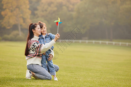 可爱的大自然可爱母女草坪上玩风车背景