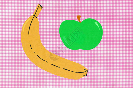 粉色方格布背景下的香蕉和苹果图片