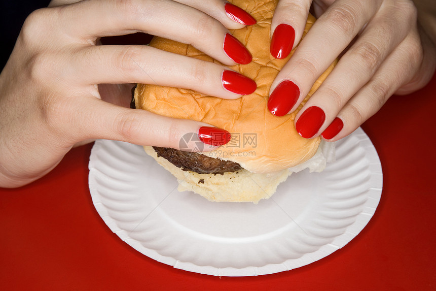 拿着汉堡的红指甲女人图片