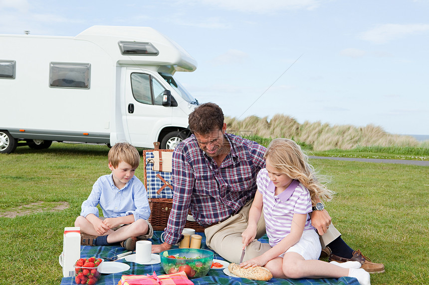 父亲和孩子们在大篷车旁野餐图片