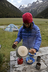 新西兰，在野营炉上做饭的中年妇女图片