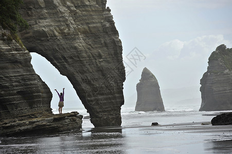 新西兰北岛海滩岩组张开双臂的年轻女子图片