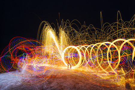 女人在夜晚用闪光装置创造黄色的圆形光路图片