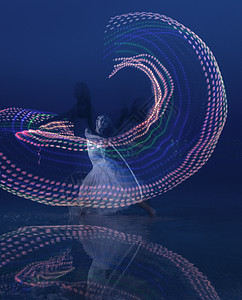 黄昏时分，带着彩灯的轮箍跳舞的女人图片