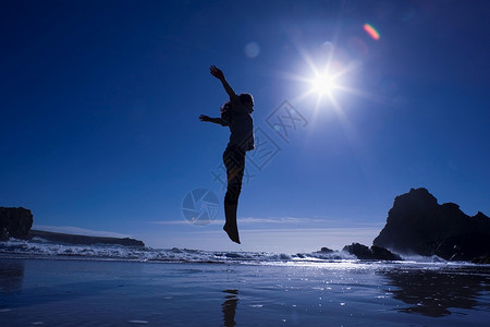 女孩在海滩上跳跃的剪影图片