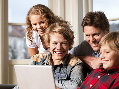 家庭wifi爸爸和儿子女儿坐在沙发上看笔记本电脑背景