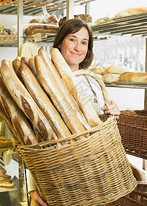 女面包师拿着一篮长棍面包图片