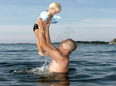 水里玩耍爷爷在水里和男孩玩耍背景