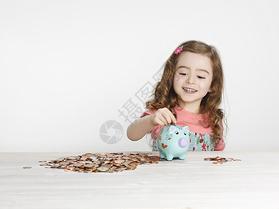 女孩把硬币放在存钱罐里图片