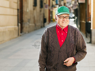 一个帽子站在街上的老年男子背景