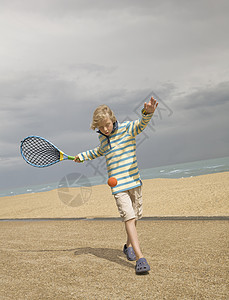 在海滩上打网球的男孩图片