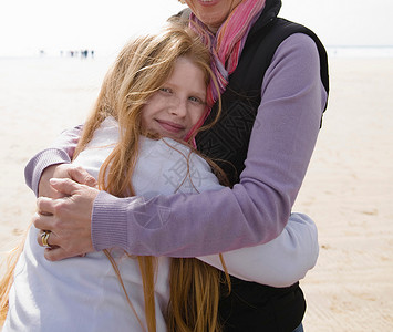 海滩上拥抱女孩的女人图片