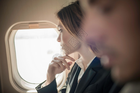 从飞机窗口向外看的女乘客图片