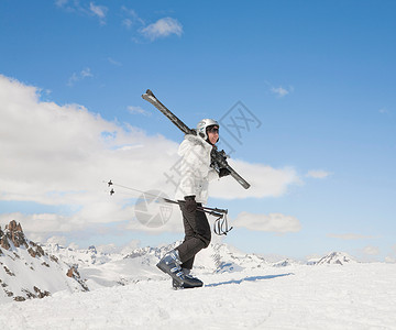 女人带着滑雪板在雪地里上山图片