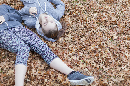 年轻女子躺在秋叶上图片