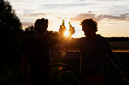 日落时喝啤酒的男人的剪影高清图片
