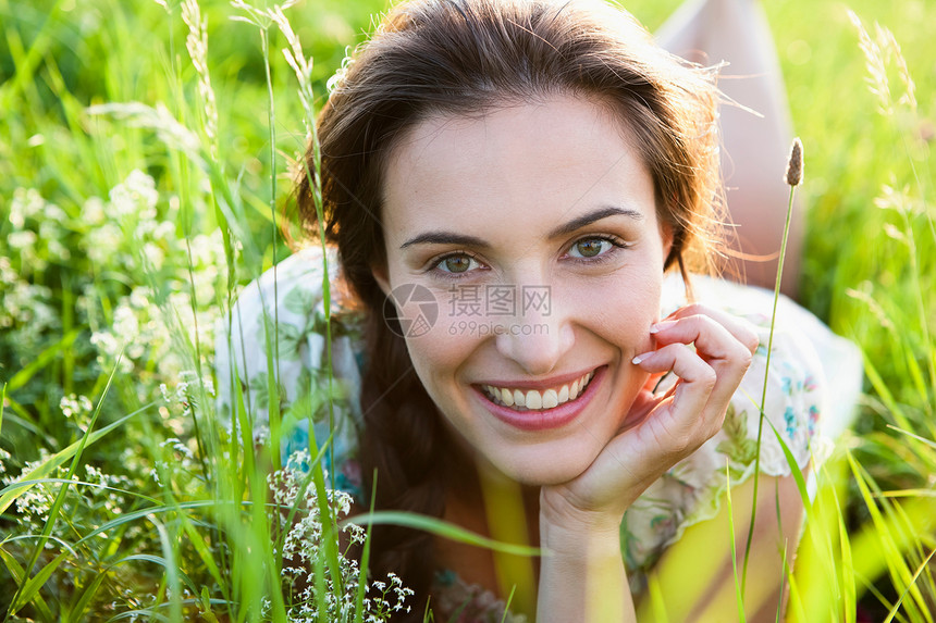 微笑的女人躺在高高的草地上图片
