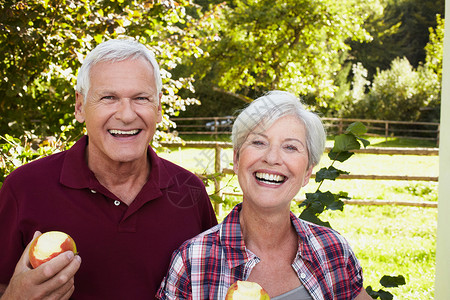 有益健康老夫妇笑着吃苹果背景
