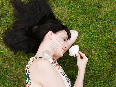 女人躺在草地上闻着玫瑰图片