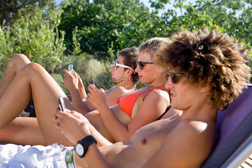 青年男女躺在阳光下玩手机图片