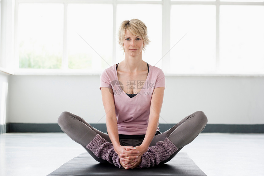 女人在瑜伽垫上伸展腿图片