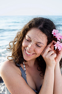 微笑的女人把花插在头发上图片