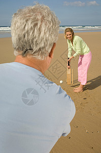 板球投手一对夫妇在海滩上打板球背景