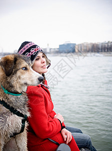 坐在河边带着狗的年轻女子图片