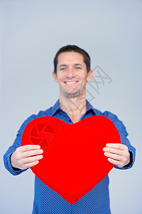 微笑的男人拿着一颗大大的红心图片