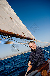 坐在帆船上微笑的男人图片