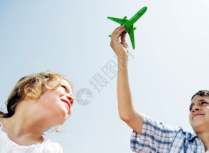 男孩和女孩抬头看玩具飞机高清图片