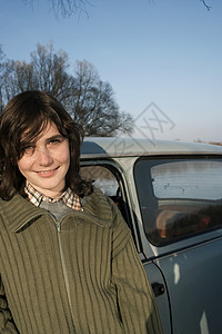 站在车旁微笑的男孩图片