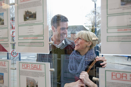 一对夫妇在窗口看房地产广告图片
