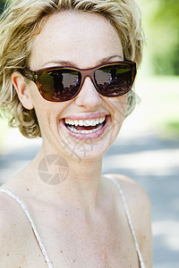 戴太阳镜的女人对着镜头微笑图片