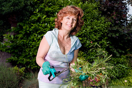 在花园里种植物的成熟女人背景图片