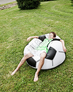 男孩在充气的巨型足球上放松图片