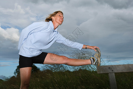女子跑步运动员在做伸展运动高清图片