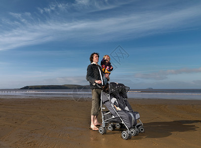 沙滩上的男人推着婴儿推车背景图片