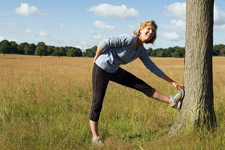女子跑步运动员在做树上伸展运动高清图片