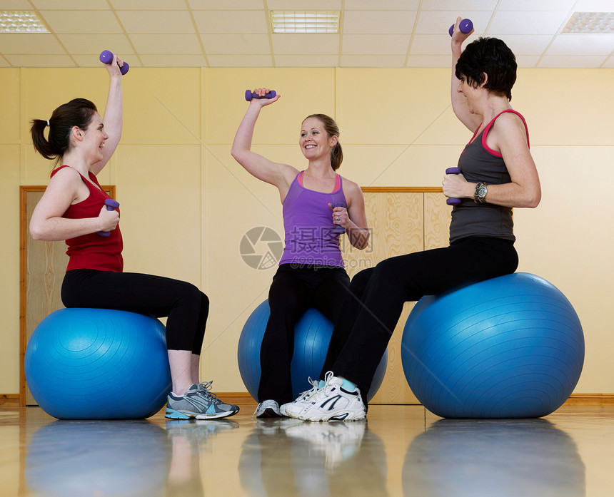 妇女在健身房举重锻炼图片