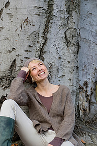 女人倚在树旁笑图片