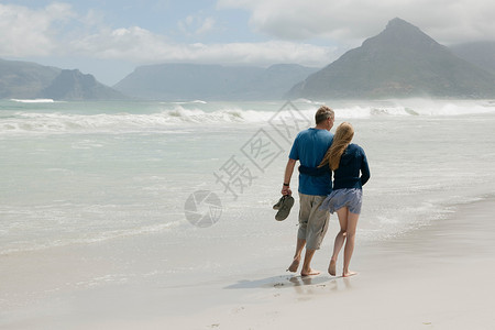 年轻女子和父亲在沙滩上散步图片