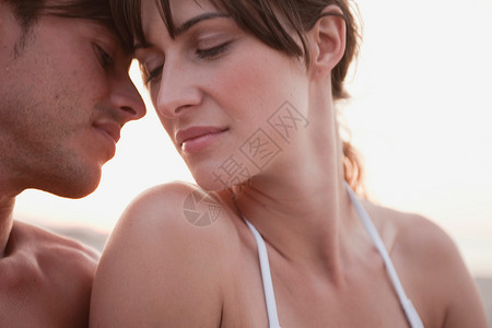 一对情侣坐在海滩上接吻图片