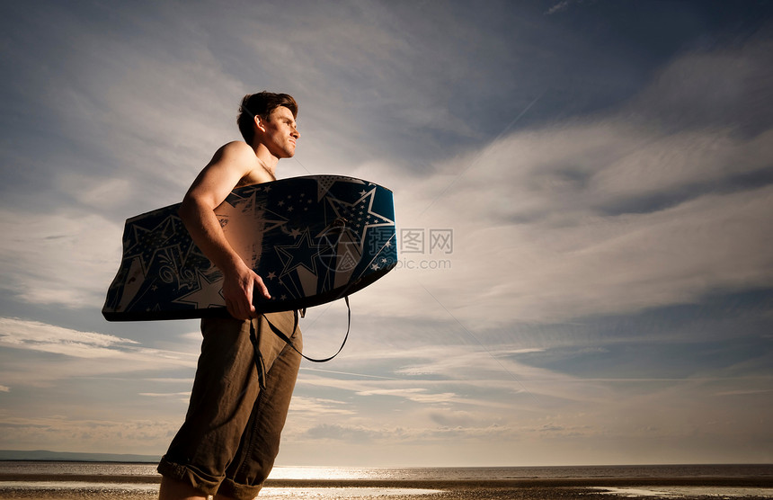 海滩上有布吉冲浪板的男人图片