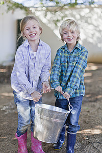 提着水桶的男孩孩子们在户外提着沉重的水桶背景